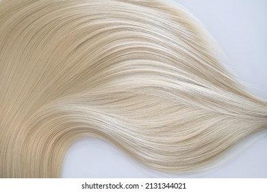 Curl female healthy hair. Concept hairdresser spa salon. strand of blond silky hair on a white background.
