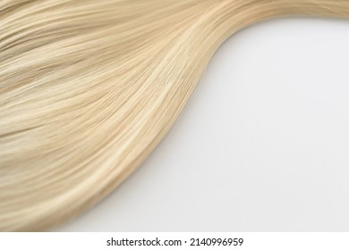 Curl female healthy hair. Concept hairdresser spa salon. strand of blond silky hair on a white background. Mock up for design