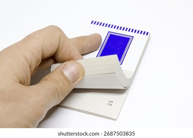 Curled stack of numbered ticket pages being flipped by a thumb, minimalist stationery isolated on white with ample copy space