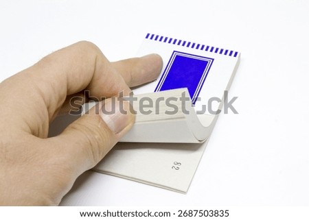 Curled stack of numbered ticket pages being flipped by a thumb, minimalist stationery isolated on white with ample copy space