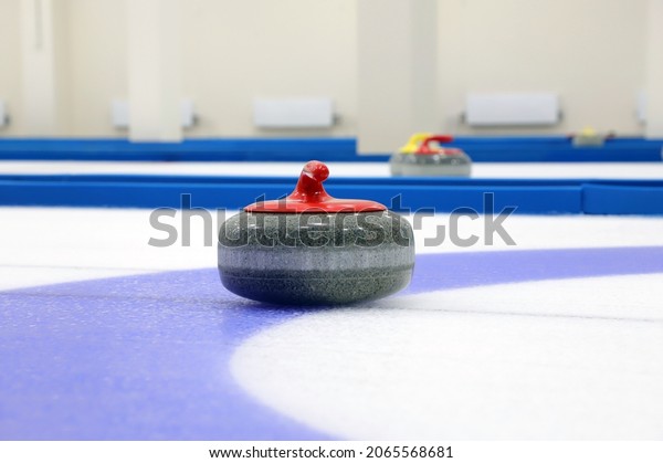 A curling stone with a red handle was shot close-up\
on ice