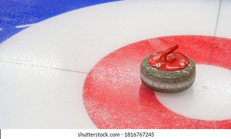 Curling, winter team olympic sport. Ice curling sheet with red and blue circle and visible pebbles. Ice rink and granite stone.