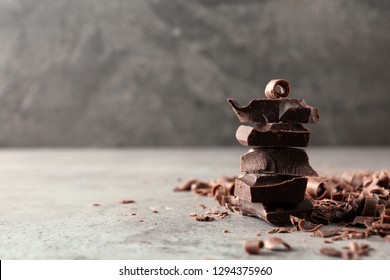 Curls and pieces of tasty chocolate on gray table. Space for text