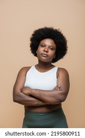 Curly African American Plus Size Woman In Crop Top Standing With Crossed Arms Isolated On Beige