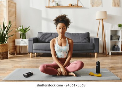 Curly African American woman in activewear practicing yoga on a mat in a cozy living room setting. - Powered by Shutterstock