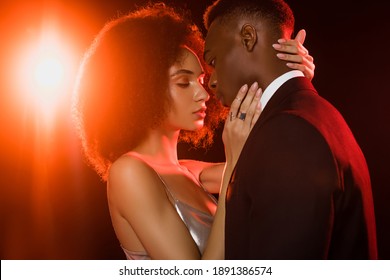 curly african american woman in dress embracing man on black