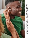 curly african american woman wearing hearing aid medical device on ear of boyfriend, accessibility