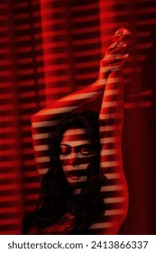 Curly black hair asian sensual model under light and shadow of blinds on skin at red glamour background. Happy japanese woman seduces sexy naked body in lace underwear posing on valentines day