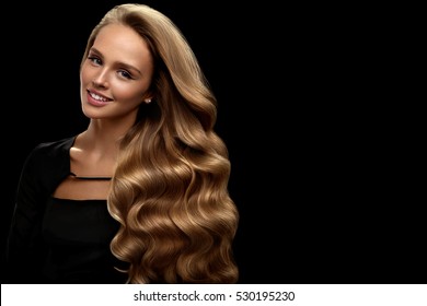 Curly Blonde Hair. Beauty Model Girl With Perfect Makeup, Gorgeous Volume And Hair Color Standing On Black Background. Beautiful Smiling Woman With Healthy Long Shiny Wavy Hair Portrait. High Quality