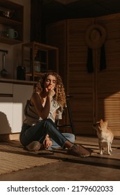 Curly Blonde Woman Sitting In Kitchen And Eating Apple With Chihuahua Dog