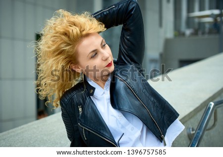 curly blonde young woman enjoying the walk in the city and feels happy in the modern cityscape