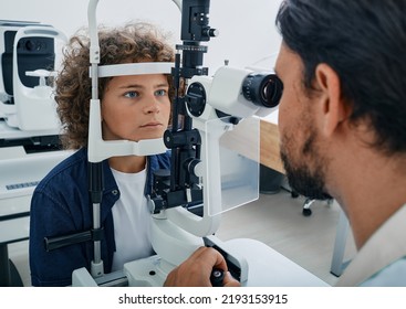 Curly Boy Getting Eye Exam At Ophthalmology Clinic With Optometrist. Checking Retina Of Male Child Eye, Ophthalmology For Children