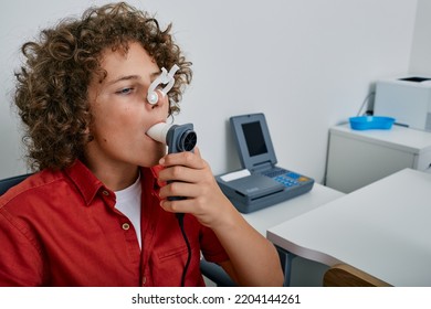 Curly boy performing pulmonary function test and spirometry using spirometer at medical clinic. Spirometry of child's lungs - Shutterstock ID 2204144261