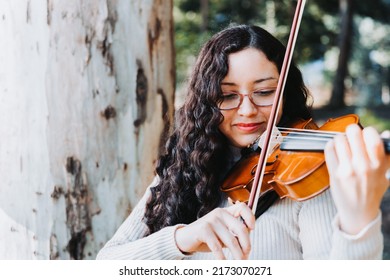 Curly Brunette Woman With Glasses Playing Violin In The Forest. Copy Space