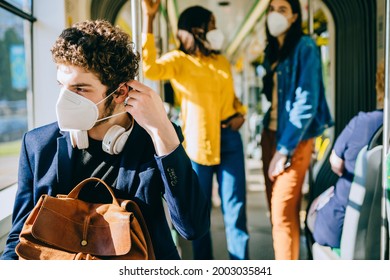 Curly caucasian man puts on a face medical mask while traveling inside public transport, tram, train or bus. Wearing mask correctly concept. - Powered by Shutterstock