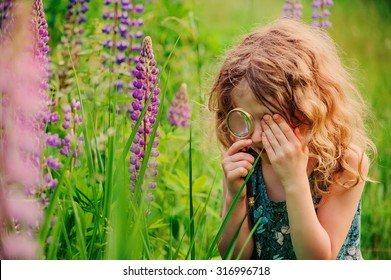 Curly Child Girl Exploring Nature With Loupe On Summer Walk