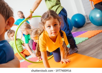 Curly girl crawling on colorful floor through hula hoops - Powered by Shutterstock