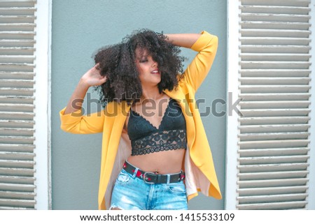 Similar – Young woman with curly hair near a modern colorful building