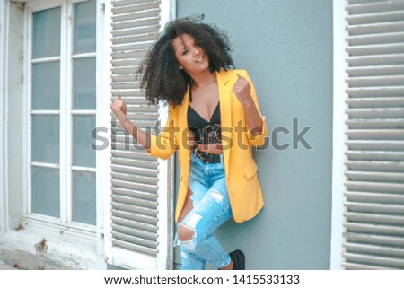 Similar – Young woman with curly hair near a modern colorful building