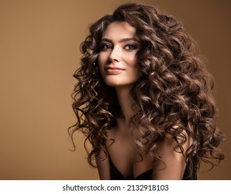 Curly Hair Model. Woman Wavy Long Hairstyle. Brunette Fashion Girl with Volume Hairdo and Natural Make up over Beige Background - Powered by Shutterstock