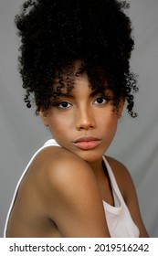 Curly Hair Woman Looking At Camera On Gray Background For Editorial And Makeup