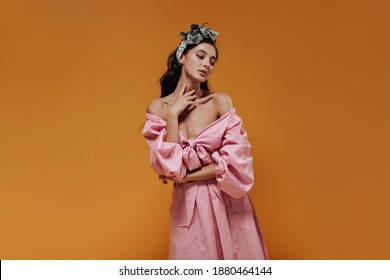 Curly Haired Lady With Green Trendy Headband In Pink Unusual Shirt And Skirt Looking Away And Posing On Isolated Backdrop..