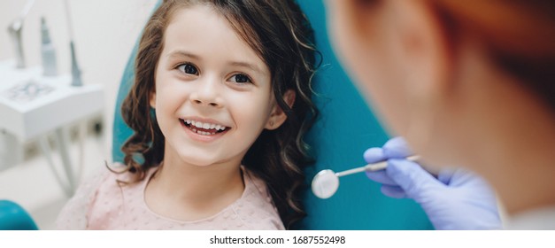 Curly haired little girl looking and smiling to the dentist after a checking up - Powered by Shutterstock