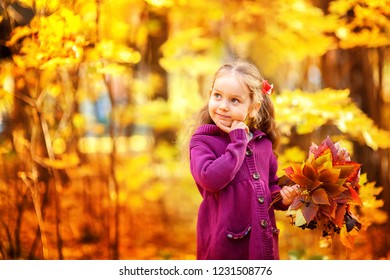 Curly happy little girl in autumn maple orange leaves