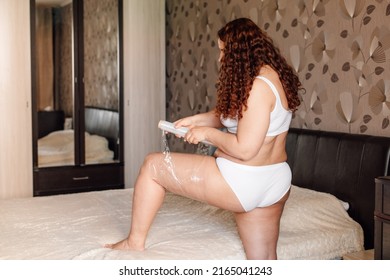 Curly Plus Size Woman In White Underwear Stand Near Bed In Bedroom And Wrap Hip With Cling Film Back View. Fat Burning Treatment Of Cellulite Thighs And Legs. Weight Loss Program, Body Wrap Procedure.