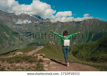 Curly young woman enjoying the view in the top of mountain on a hot summer day. Lifestyle concept. Back view. mountain landscape. Freedom concept.