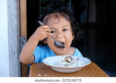 Curly-haired multiracial boy sitting having rice breakfast. Asian kid confident - Powered by Shutterstock