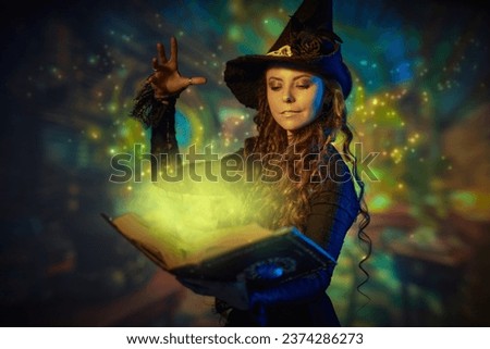A curly-haired young witch in a black hat and black dress conjures with a magic book of spells. Wonderful world of magic. Halloween. Magical background.