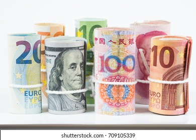 Currencies and money exchange trading concepts. The rolls of various currencies US Dollar, Euro and Chinese yuan banknotes with white rope band isolated on white background.