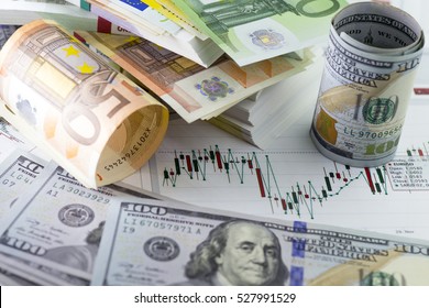 Currency Exchange Trading. Hundred Us Dollar Bill In Foreground. Piles Of Euro Banknotes In Background. Currency Us Eur Exchange Chart Under The Bills. Fifty Euro Banknote, Hundred Dollar Bill Rolled