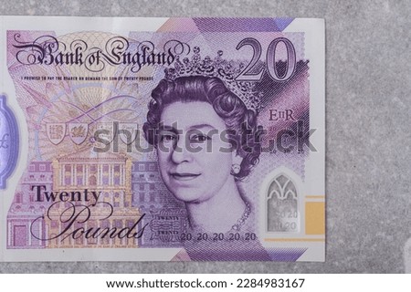 Currency of Great Britain (England) pound. Banknotes with denomination and 20 images of Queen Elizabeth portrait on a gray background