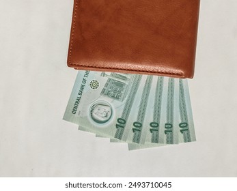 Currency notes, UAE Emirates currency 10 aed Dirhams, Closeup of UAE Ten dirhams currency notes, paper money 10 aed dirhams.
Brown leather wallet with 10 dirhams banknotes, UAE Emirati 10 aed notes