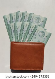Currency notes, UAE Emirates currency 10 aed Dirhams, Closeup of UAE Ten dirhams currency notes, paper money 10 aed dirhams.
Brown leather wallet with 10 dirhams banknotes, UAE Emirati 10 aed notes