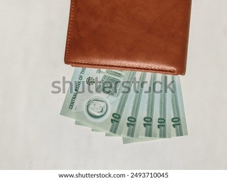 Currency notes, UAE Emirates currency 10 aed Dirhams, Closeup of UAE Ten dirhams currency notes, paper money 10 aed dirhams.
Brown leather wallet with 10 dirhams banknotes, UAE Emirati 10 aed notes