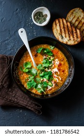 Curried red lentil tomato and coconut soup - delicious vegetarian food on dark background, top view  