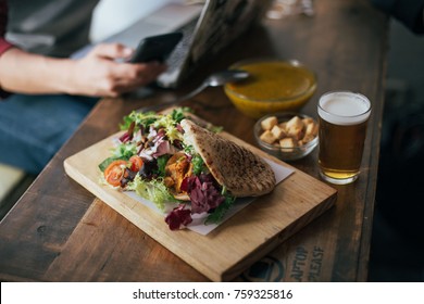 Curry Chicken Sandwich In Pita Bread Served With Croutons, Side Salad, Beer And Cream Vegetable Soup. Healthy Lunch Break Meal Menu In Cafe Or Business Bar, On Wooden Table 