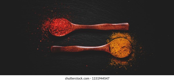 Curry and chili pepper spices, wooden spoons, black stone background, food background, top view and toned image - Powered by Shutterstock