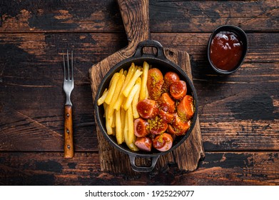 Currywurst Street Food Meal, Curry Spice On Wursts Served French Fries In A Pan. Dark Wooden Background. Top View