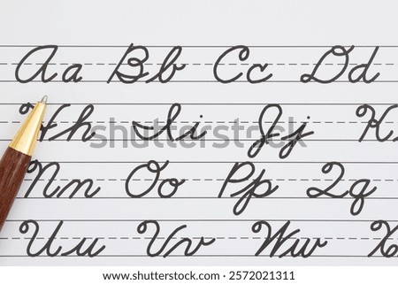 Cursive writing practice sheet with alphabet letters and a pen for learning handwriting skills. Perfect for educational content.