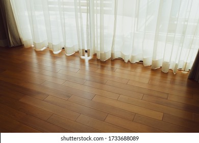 Curtain decorated beautifully in the room, Bright morning sun in the window through the curtains, White elegant curtains in a wood-floor bedroom with the morning sun shining through for the background