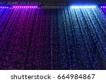 curtain of falling water with colorful led light on dark background, selective focus