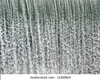 A Curtain Of Water Falling Over A Dam