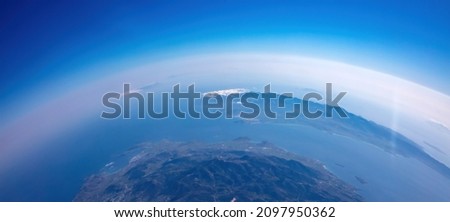 Curvature of planet earth. Aerial shot. Blue sky and clouds over island in the ocean. Space, science concept