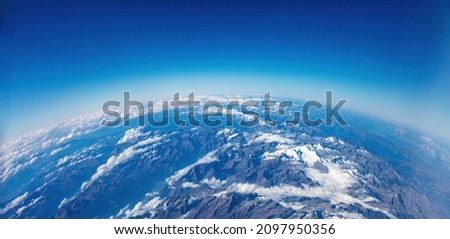 Curvature of planet earth. Aerial view. Blue sky and clouds over high snowed mountaint peaks. Geography, science concept