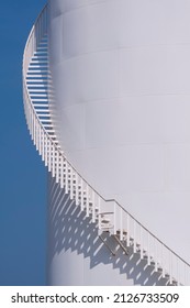 Curve Line Of Spiral Staircase On White Oil Storage Fuel Tank With Blue Clear Sky In Vertical Frame