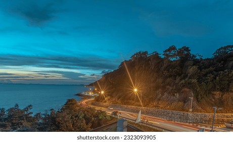 The curve of the long exposure light trail on the coast road with the sea and mountains, Chanthaburi's scenic Nang Phaya hill. - Powered by Shutterstock